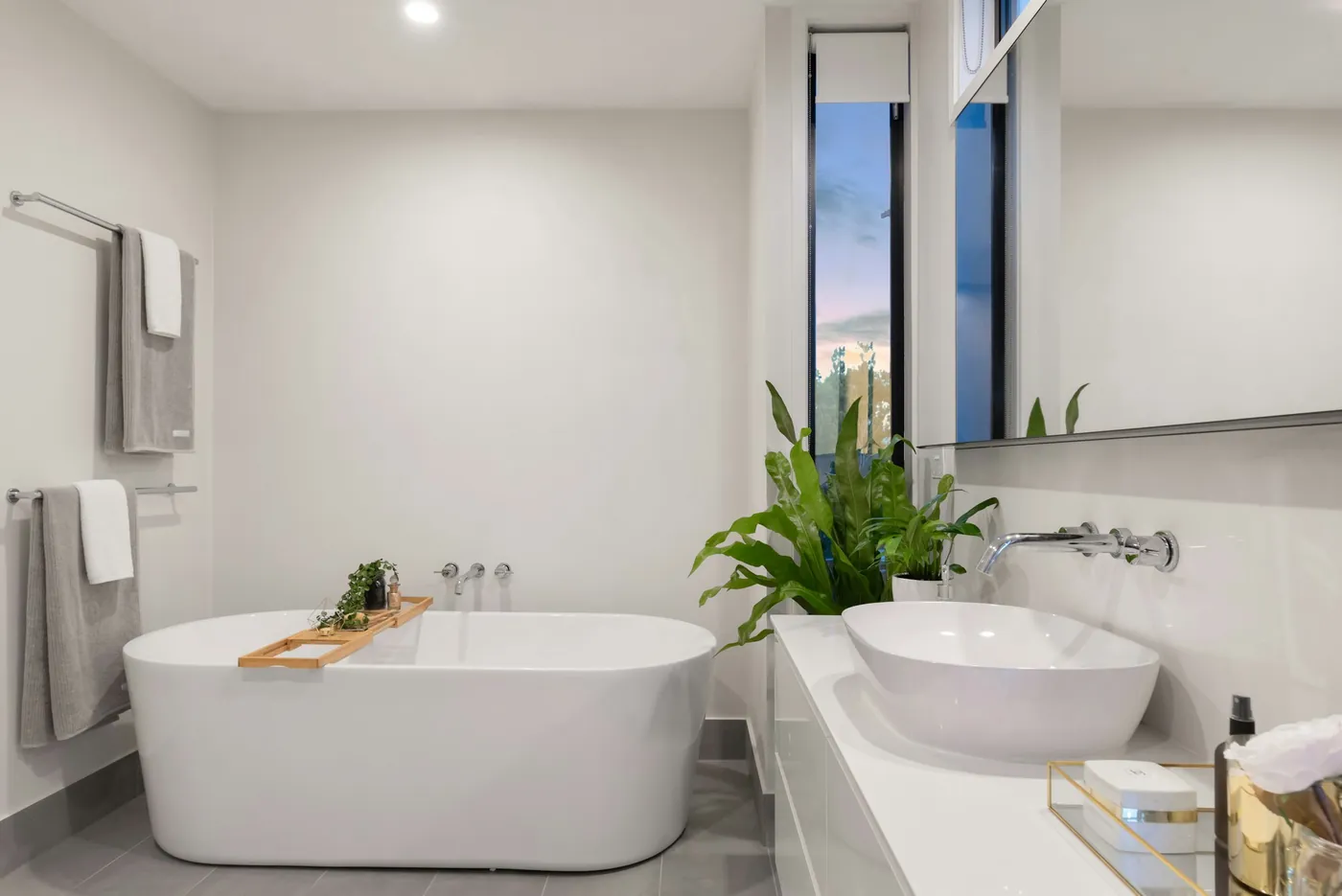 A spotless modern bathroom with a freestanding tub and folded towels